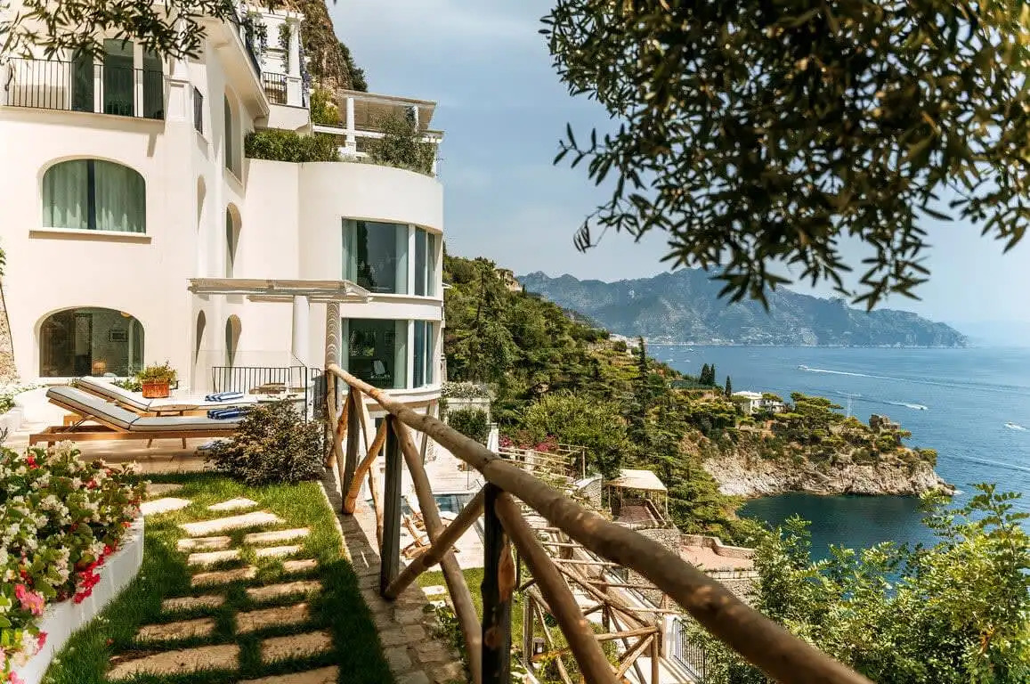 Luxurious terrace with lounge chairs overlooking the Amalfi Coast hills and Mediterranean Sea